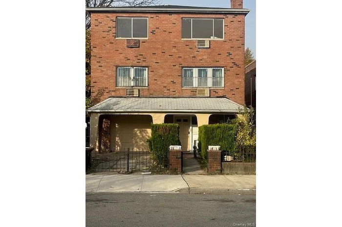 View of front of property with brick siding, a fenced front yard, and a chimney