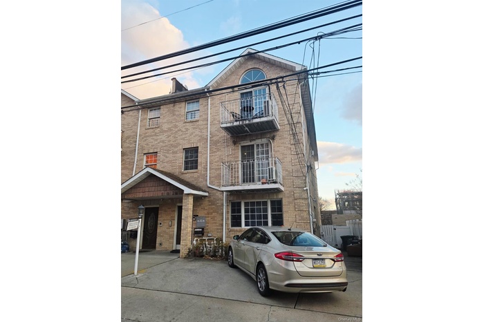 View of front of property with brick siding, a balcony, and a chimney