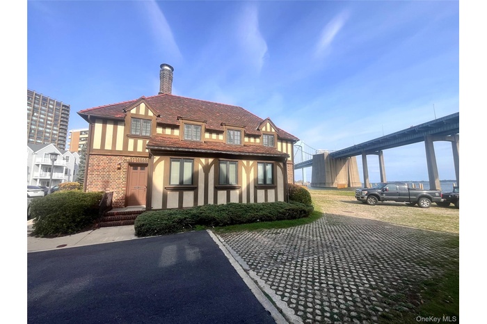 Back of property featuring stucco siding, uncovered parking, brick siding, and a chimney