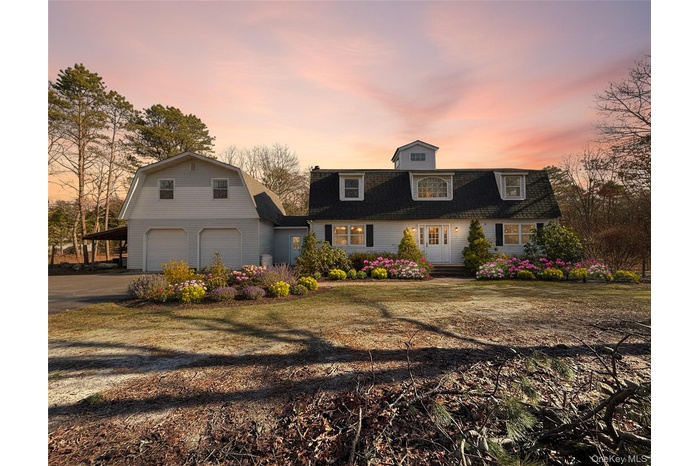 Dutch colonial with a gambrel roof, driveway, roof with shingles, and a front lawn