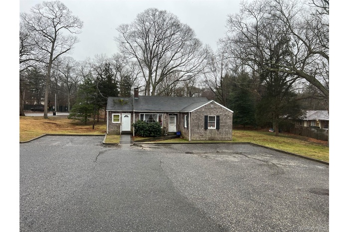 View of front of house featuring a front lawn, view of scattered trees, and a chimney