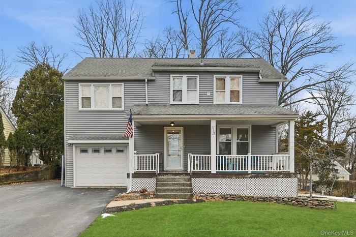 View of front of home featuring covered porch, a shingled roof, a front yard, asphalt driveway, and an attached garage