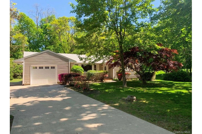 View of front of home with a front yard, an attached garage, and concrete driveway