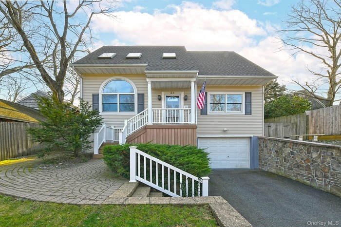 View of front of house with roof with shingles, asphalt driveway, a patio area, and a garage