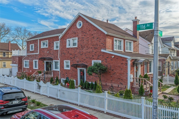 View of front facade with a fenced front yard, brick siding, a chimney, and a residential view