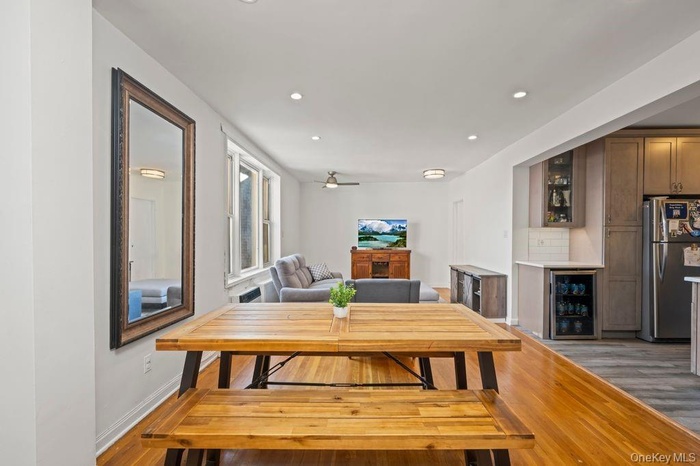 Dining area with light wood-type flooring, wine cooler, recessed lighting, a dry bar, and a ceiling fan