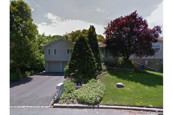View of front of home featuring a front yard, driveway, and a garage