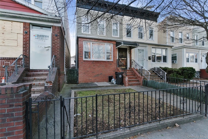 View of front of house with a gate, a fenced front yard, and brick siding