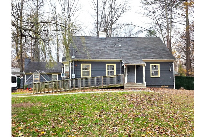 Cape cod-style house featuring a chimney and a front lawn