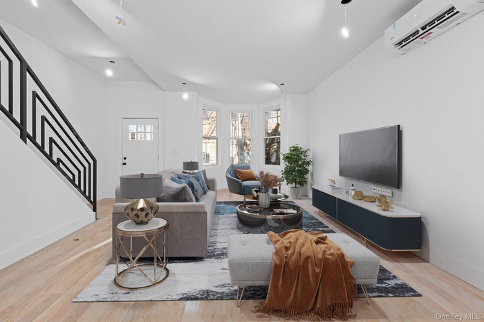 Living room with an AC wall unit, stairway, and light wood-type flooring