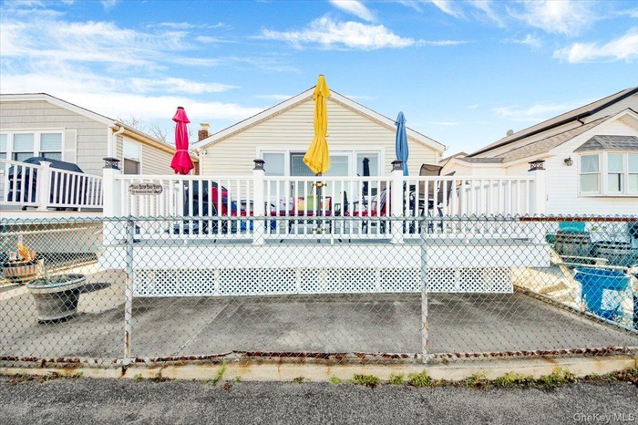 Bungalow-style house featuring a wooden deck, a patio area, and a fire pit