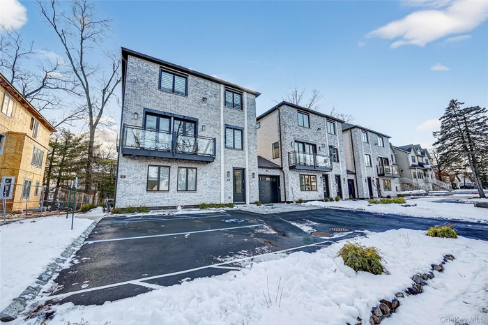 Snow covered property featuring a residential view and uncovered parking