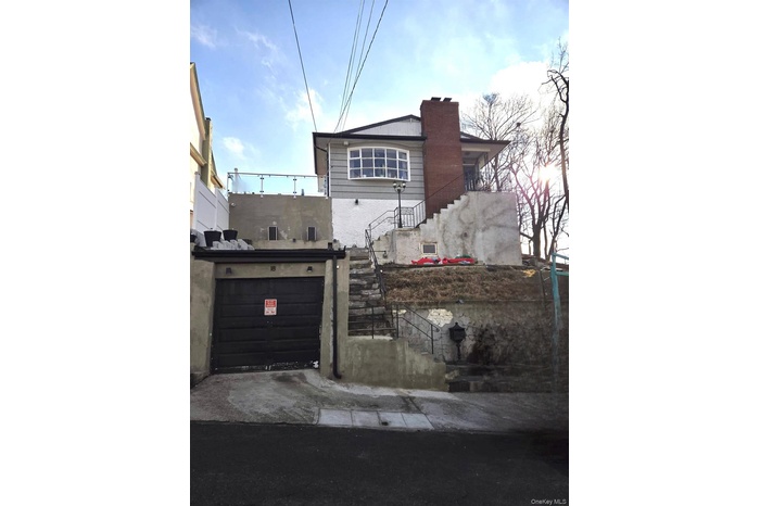 View of side of home with stairway, a garage, and a chimney