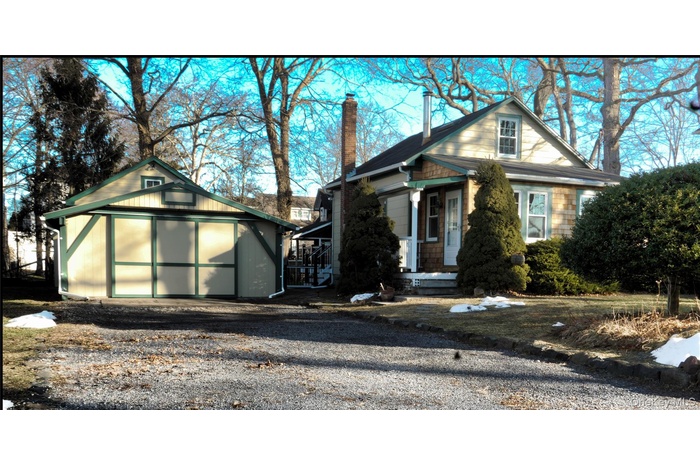 View of front of home featuring a chimney, a storage shed, and gravel driveway