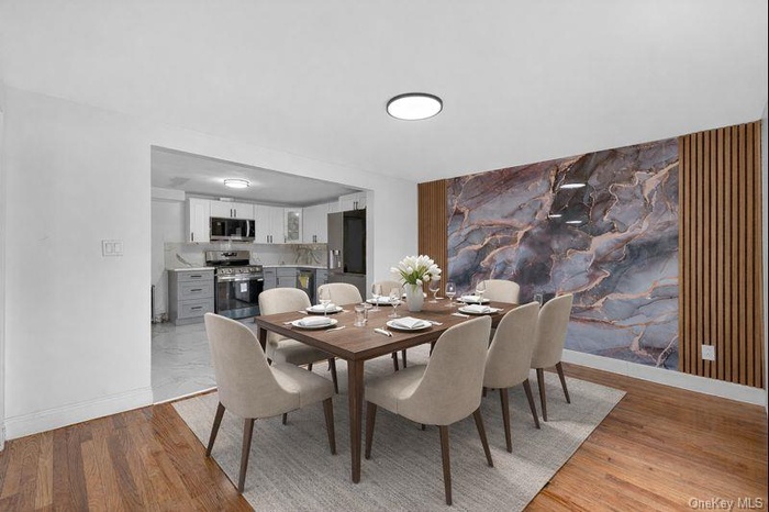 Dining area with an accent wall and light wood finished floors