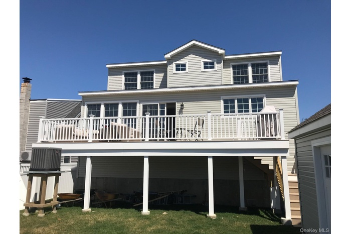 Rear view of house with a wooden deck and a lawn