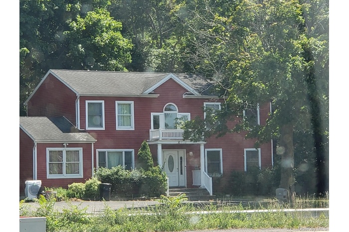 View of front of home featuring a balcony and roof with shingles