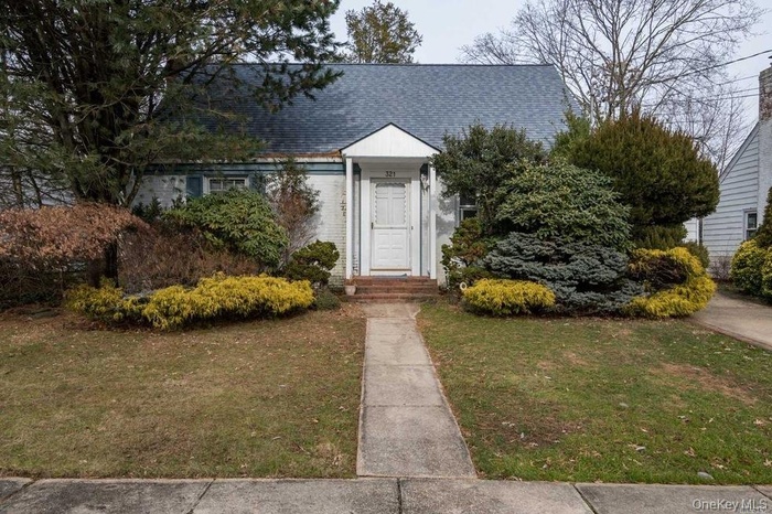 View of front facade with a front yard, brick siding, and roof with shingles