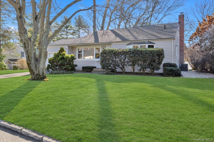 View of front of house with a chimney, a front yard, and roof with shingles