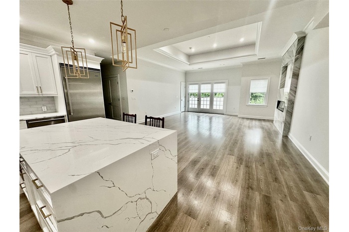 Kitchen with decorative light fixtures, white cabinets, recessed lighting, open floor plan, and a raised ceiling
