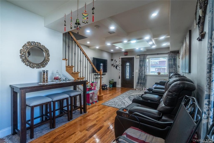 Living room with stairs, wood finished floors, and recessed lighting