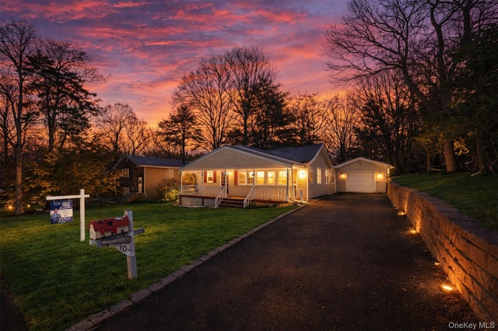 View of front of home featuring an outdoor structure, a yard, a garage, and view of scattered trees