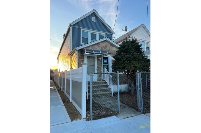 View of front of house featuring a fenced front yard, stone siding, and a gate
