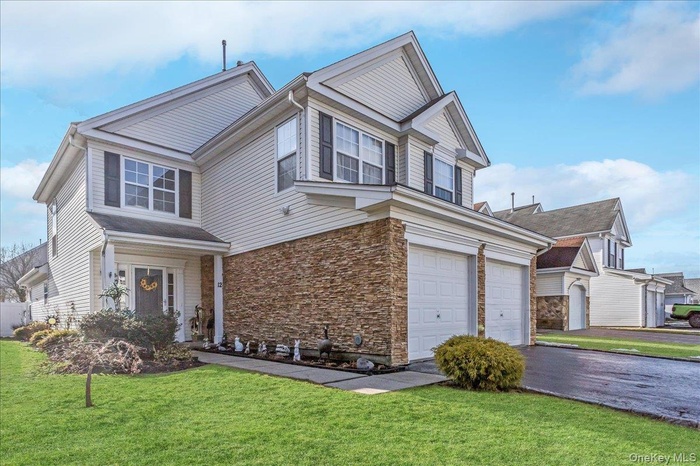 Traditional-style house featuring a front lawn, driveway, and stone siding