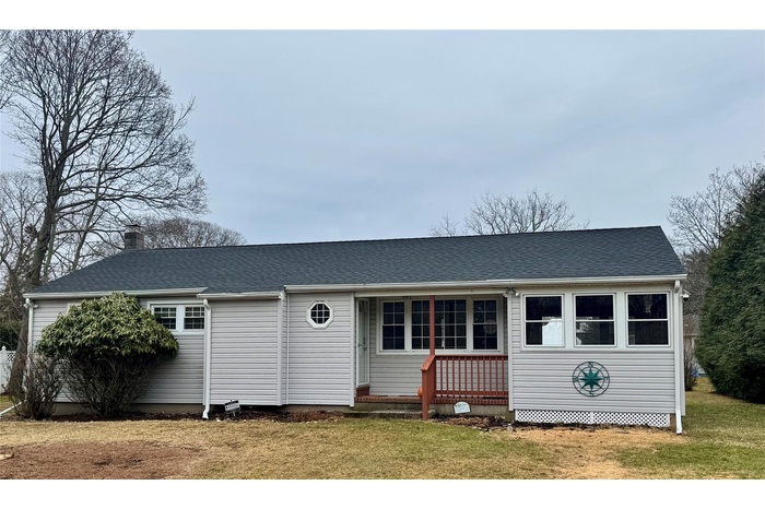 View of front facade featuring a shingled roof and a front yard