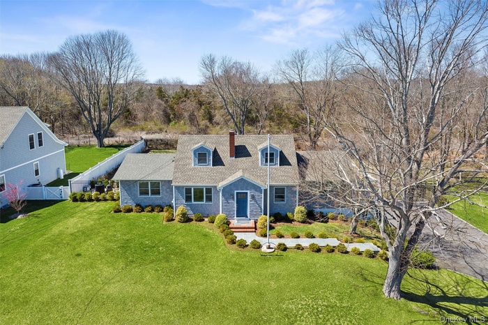 Cape cod home featuring a front yard, roof with shingles, fence, and a chimney