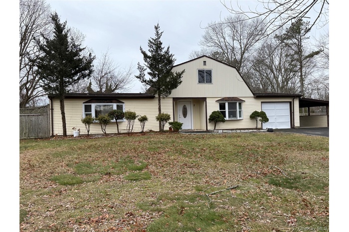 View of front facade featuring a gambrel roof, driveway, an attached garage, and a carport