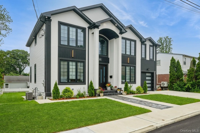 View of front of home featuring driveway, a front yard, and stucco siding