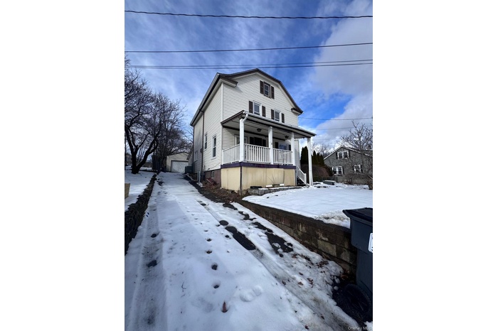 View of front of house featuring covered porch, an outdoor structure, and a detached garage