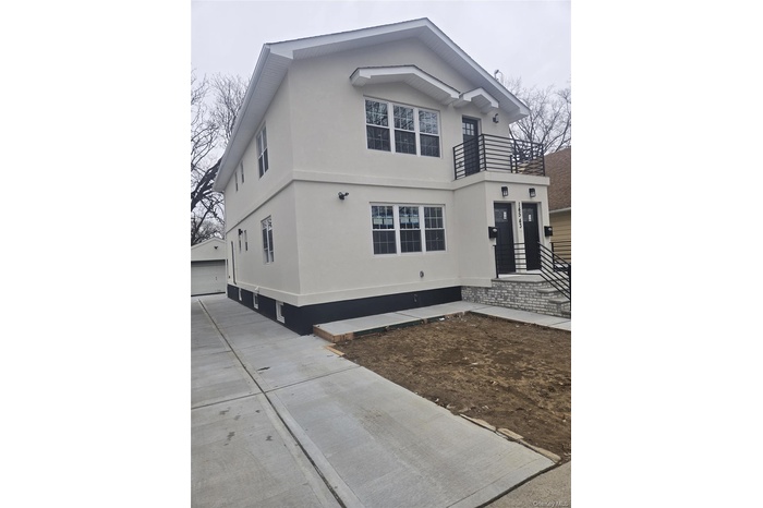 View of front facade featuring stucco siding, a detached garage, and a balcony