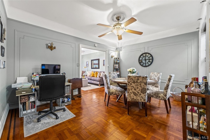 Dining area with a decorative wall, ceiling fan, and a desk