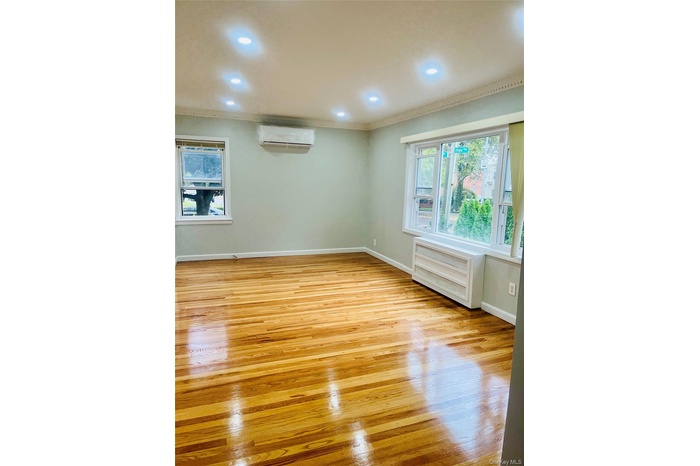 Spare room featuring light wood finished floors, ornamental molding, recessed lighting, and a wall mounted air conditioner