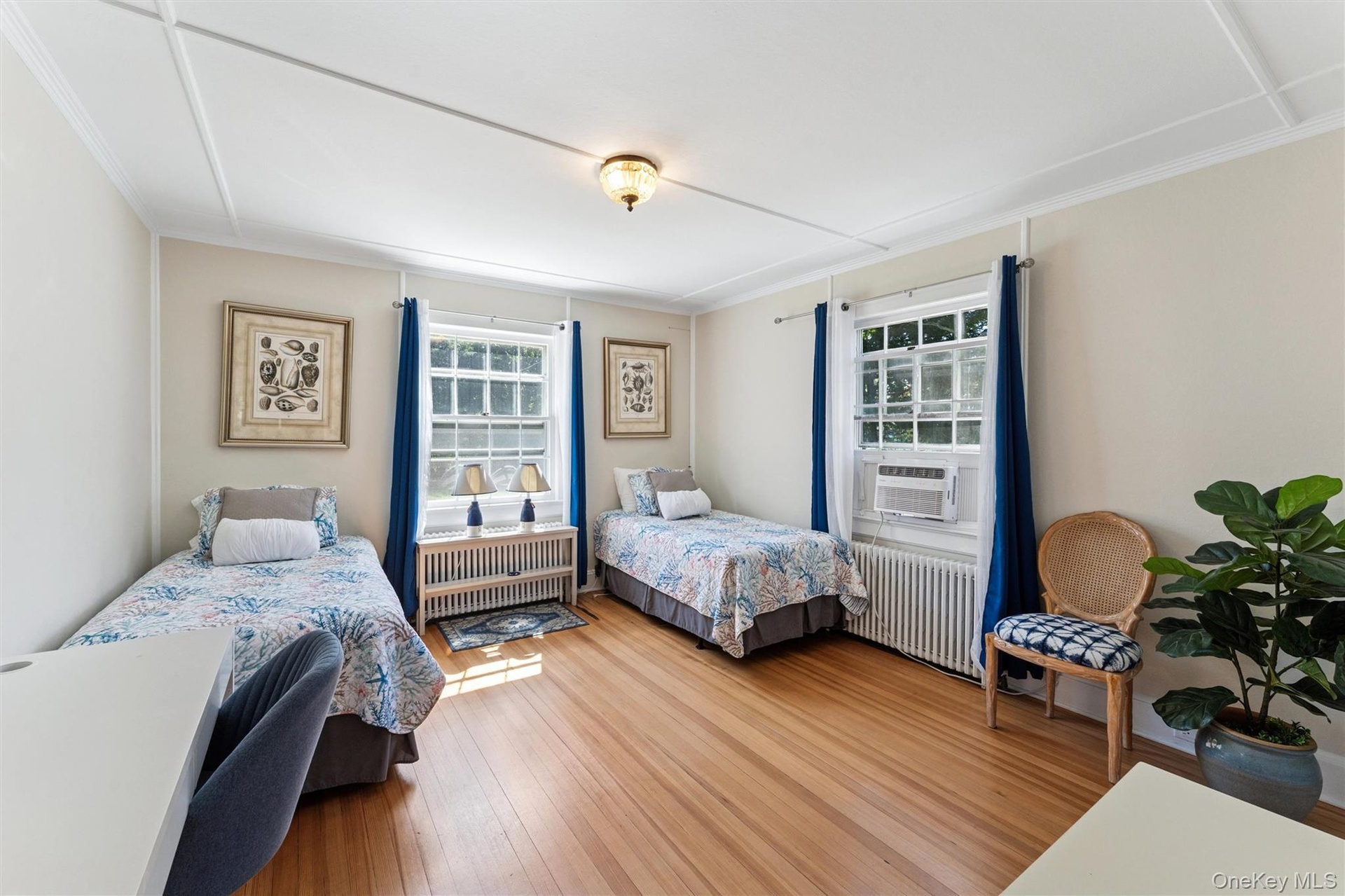 Bedroom with radiator heating unit, wood finished floors, cooling unit, and ornamental molding