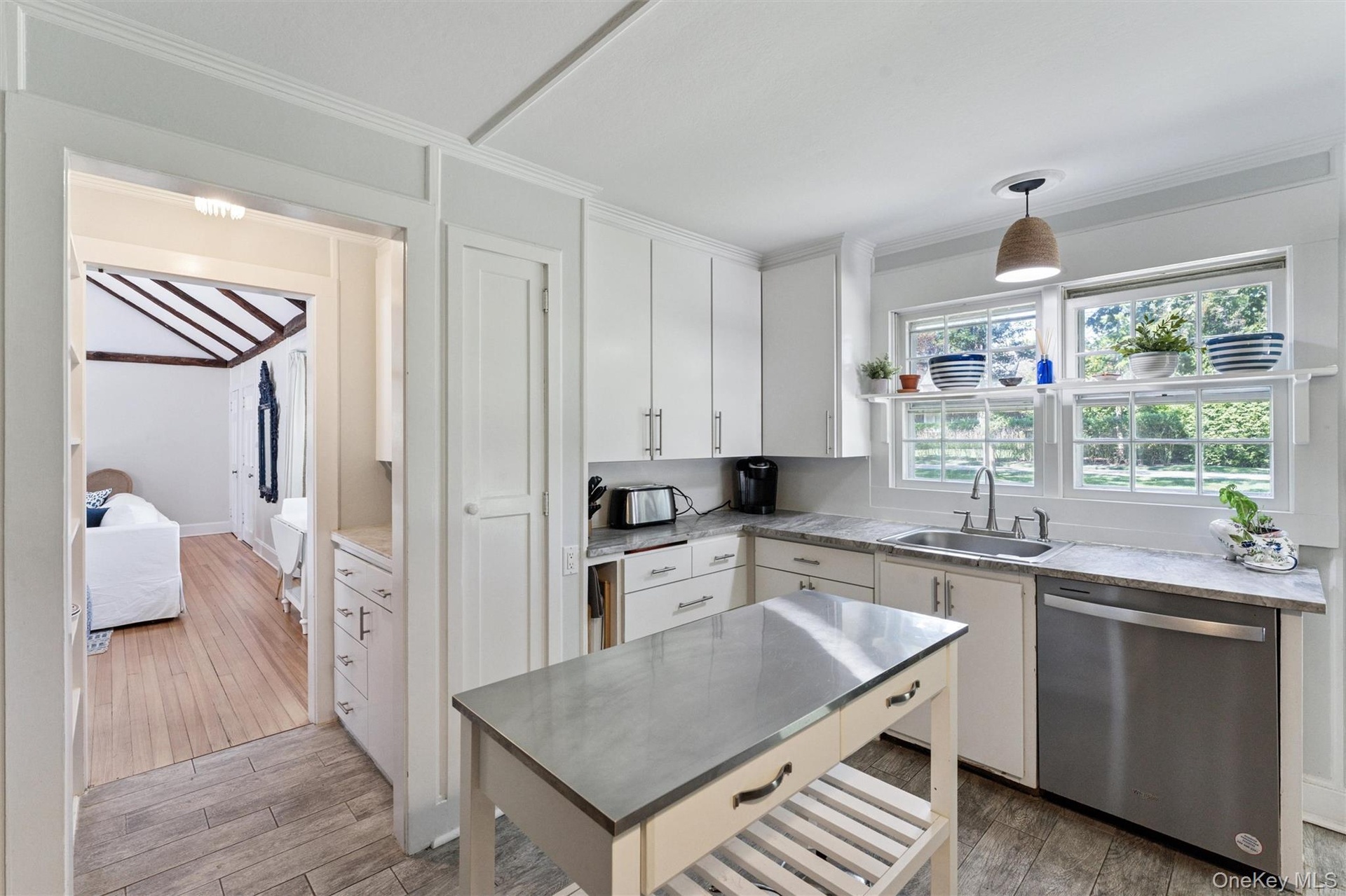 Kitchen featuring dishwasher, light wood finished floors, decorative light fixtures, white cabinetry, and ornamental molding