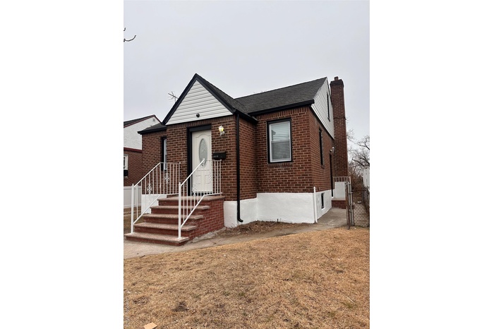 View of front of house featuring brick siding, a shingled roof, and a gate