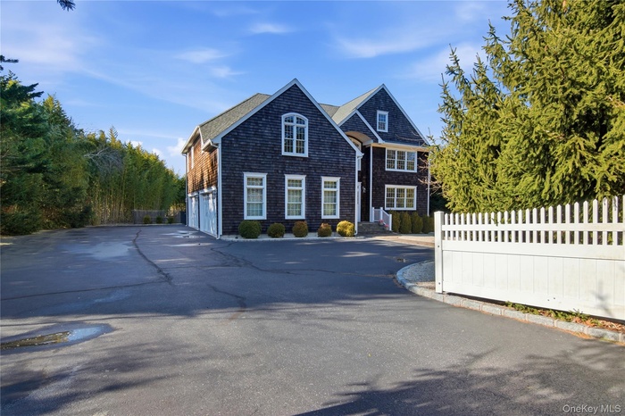 Shingle-style home featuring a garage and driveway
