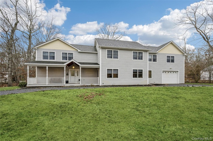 View of front of home featuring covered porch, a front yard, roof with shingles, and a garage