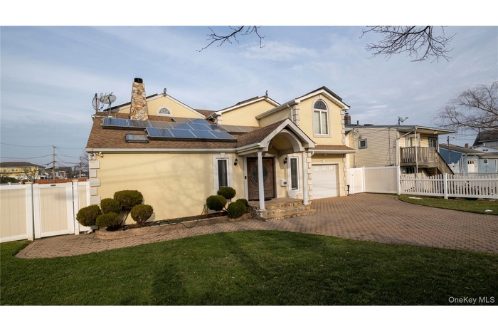 View of front of house with stucco siding, decorative driveway, a chimney, and roof mounted solar panels