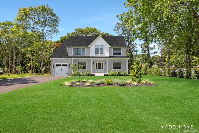 View of front of home with a front yard, driveway, a porch, and roof with shingles