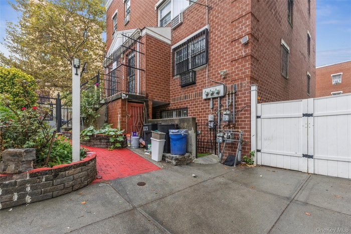 View of side of property featuring brick siding, a gate, and cooling unit