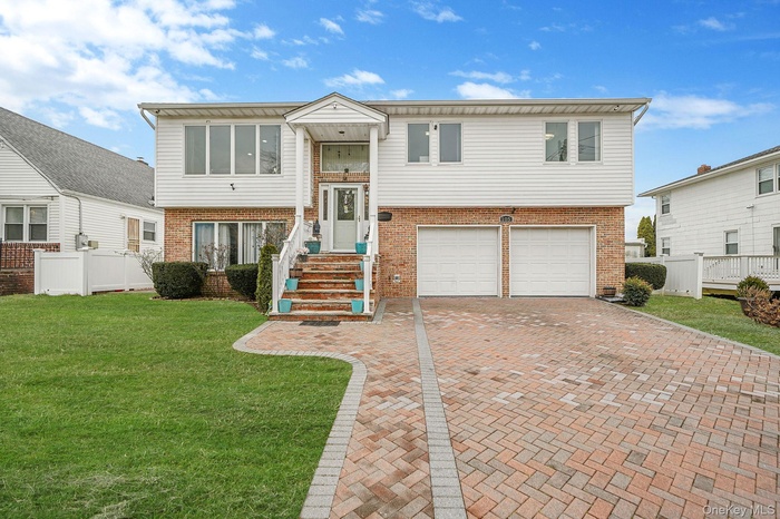 Bi-level home with brick siding, decorative driveway, and a garage