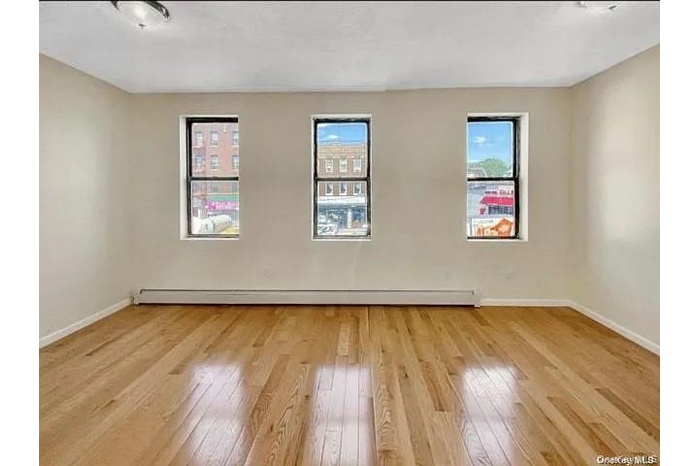 Unfurnished room featuring light wood-type flooring and a baseboard radiator
