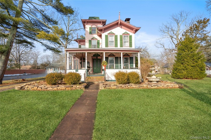 Italianate-style house featuring a porch and a front yard