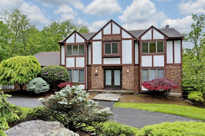 View of front of house featuring stucco siding, french doors, brick siding, and a shingled roof