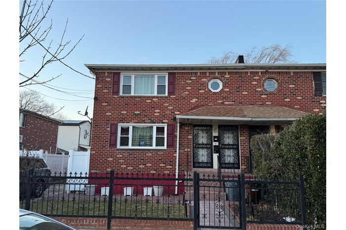 Traditional-style home featuring brick siding, a fenced front yard, and a gate