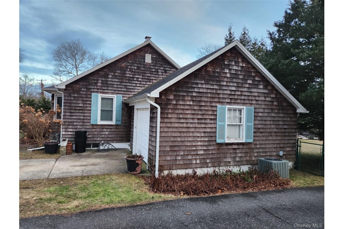 View of property exterior featuring a garage, driveway, and a patio